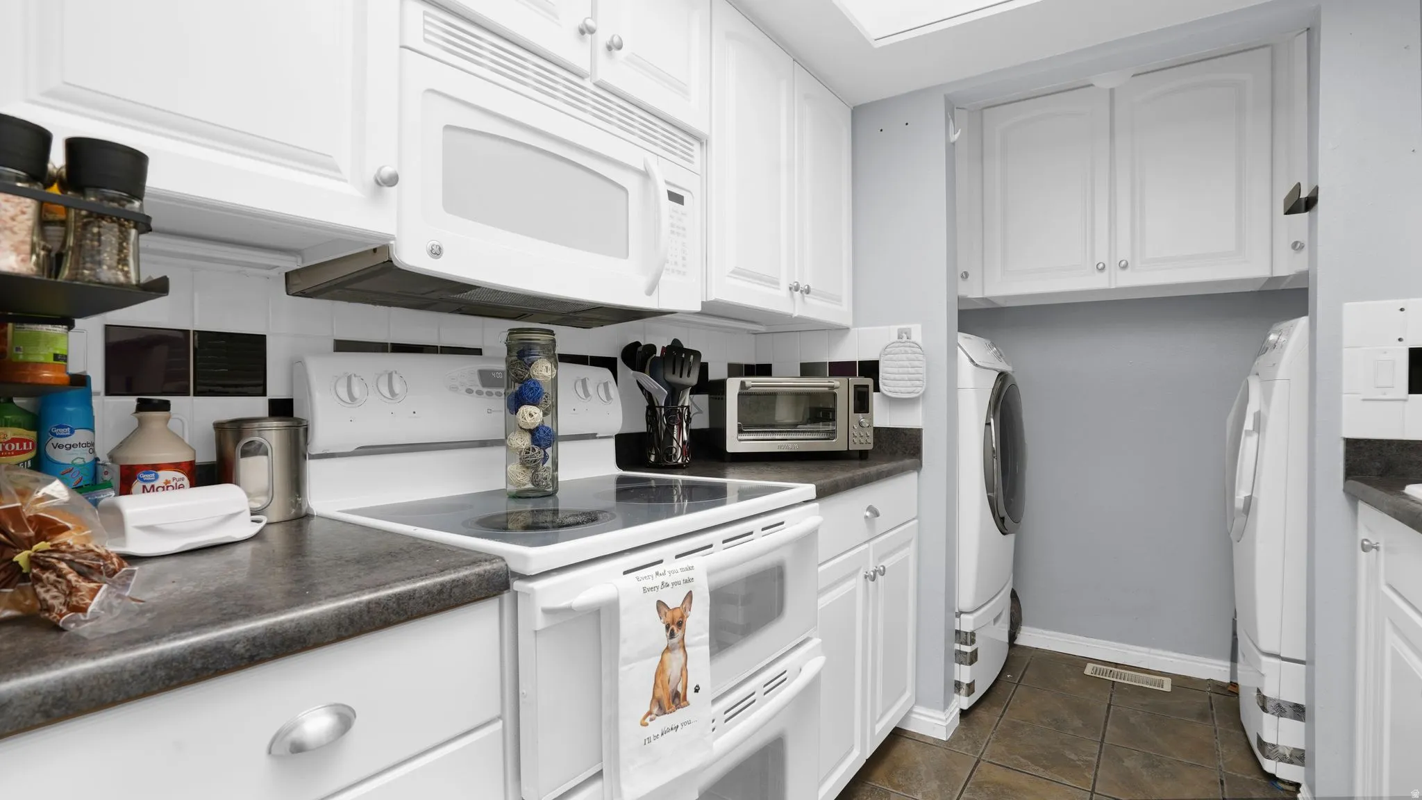 Kitchen featuring white cabinetry and dark countertops