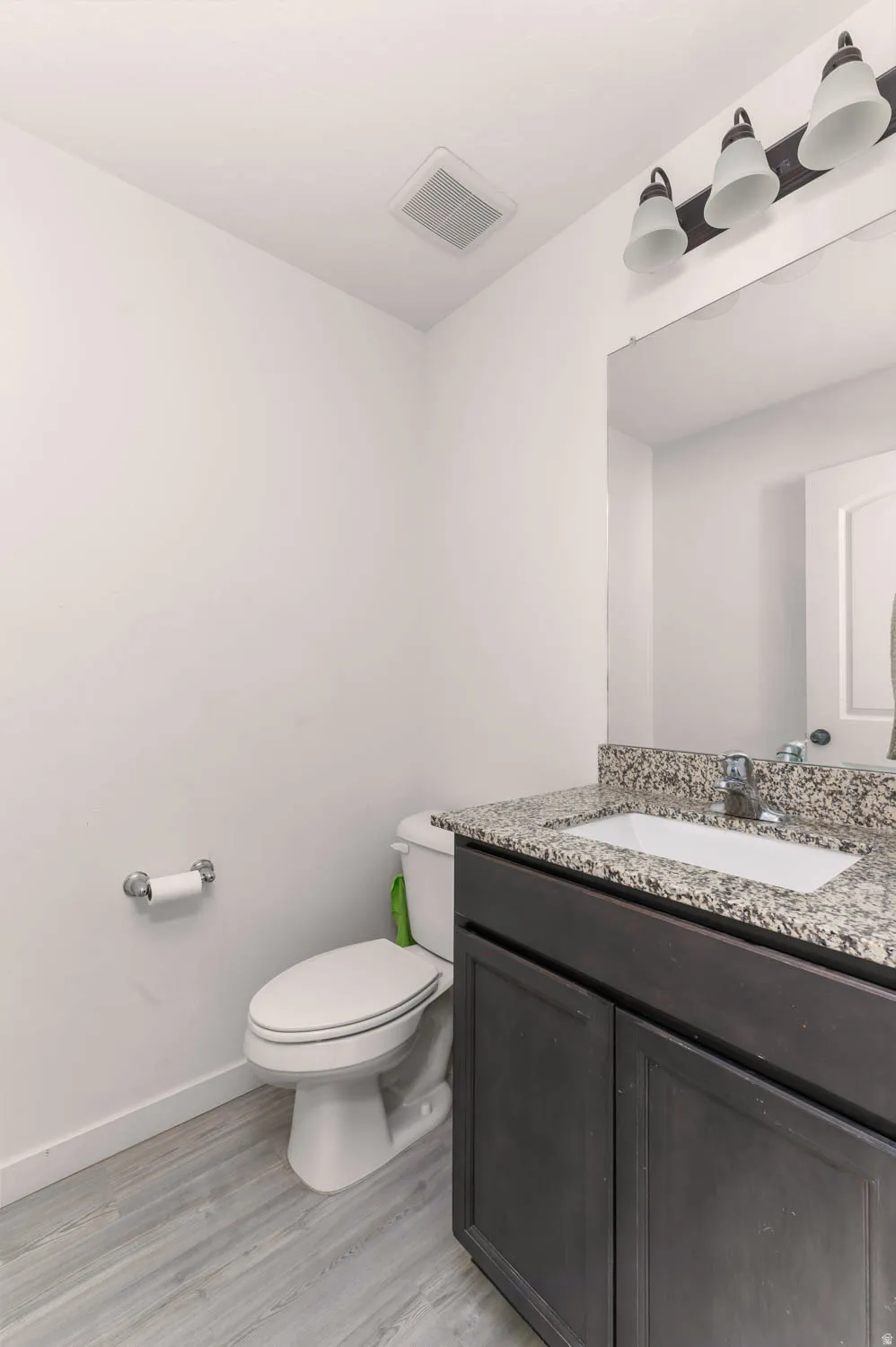 Vanity with granite-style countertop and integrated sink, complemented by a three-light fixture