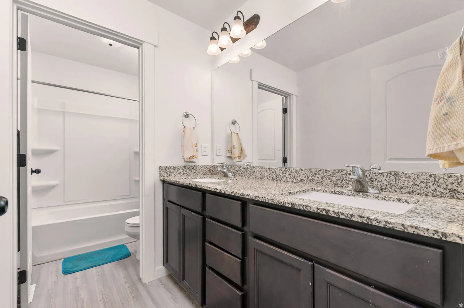 Double vanity with dark wood cabinetry and granite-style countertops