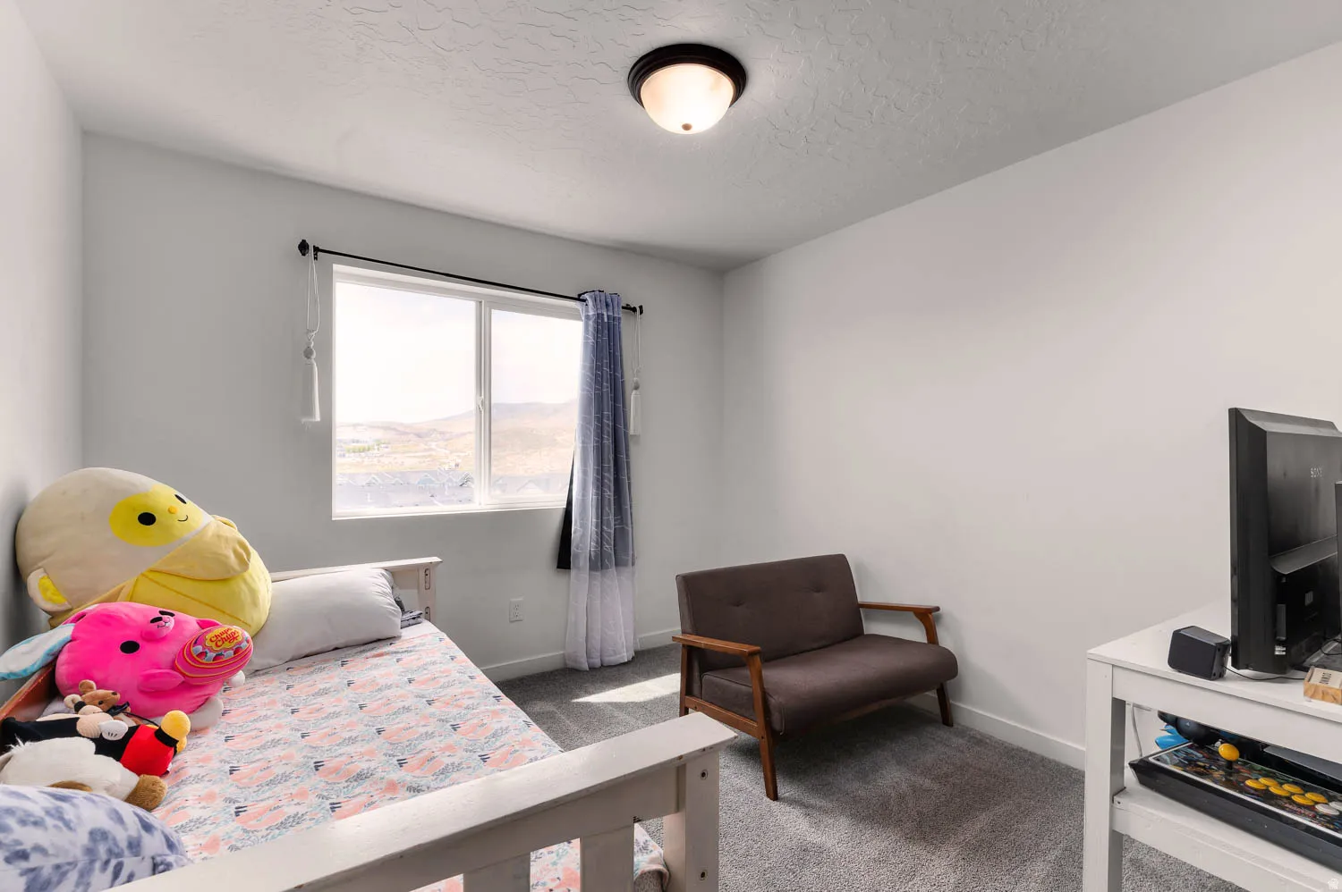Interior room featuring light gray walls, textured ceiling, a single window with dark curtain rod and white blinds, and gray carpeting