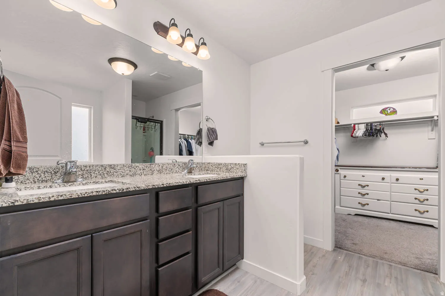 Dual vanity with granite-style countertop, undermount sinks, and dark wood-finish cabinetry