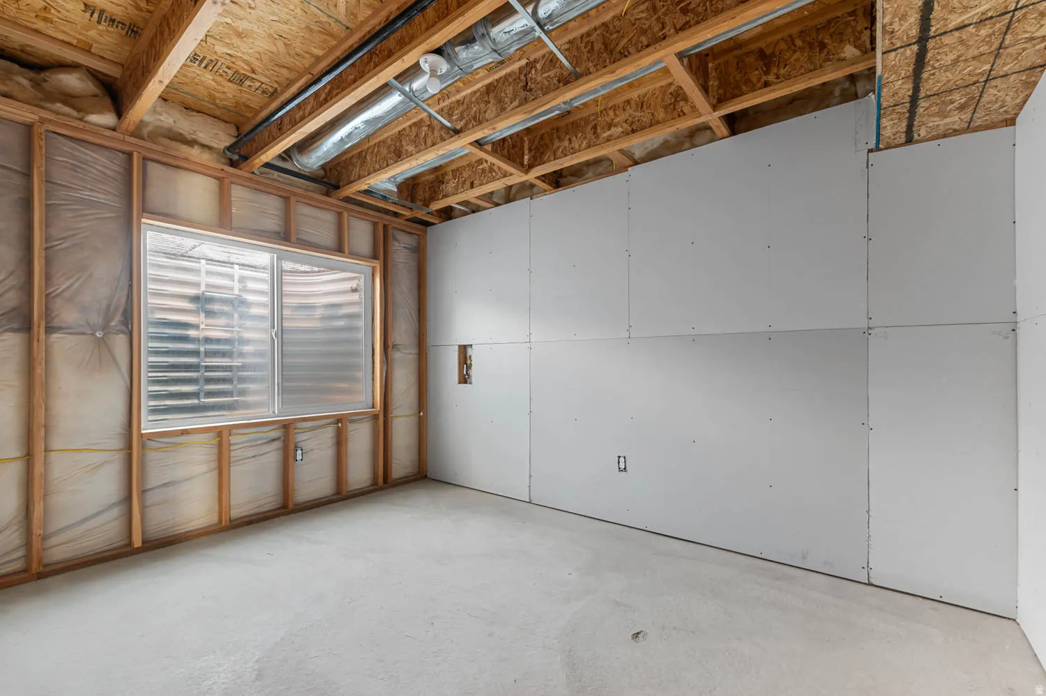 Unfinished basement space featuring exposed wooden ceiling joists, ductwork, and a concrete floor