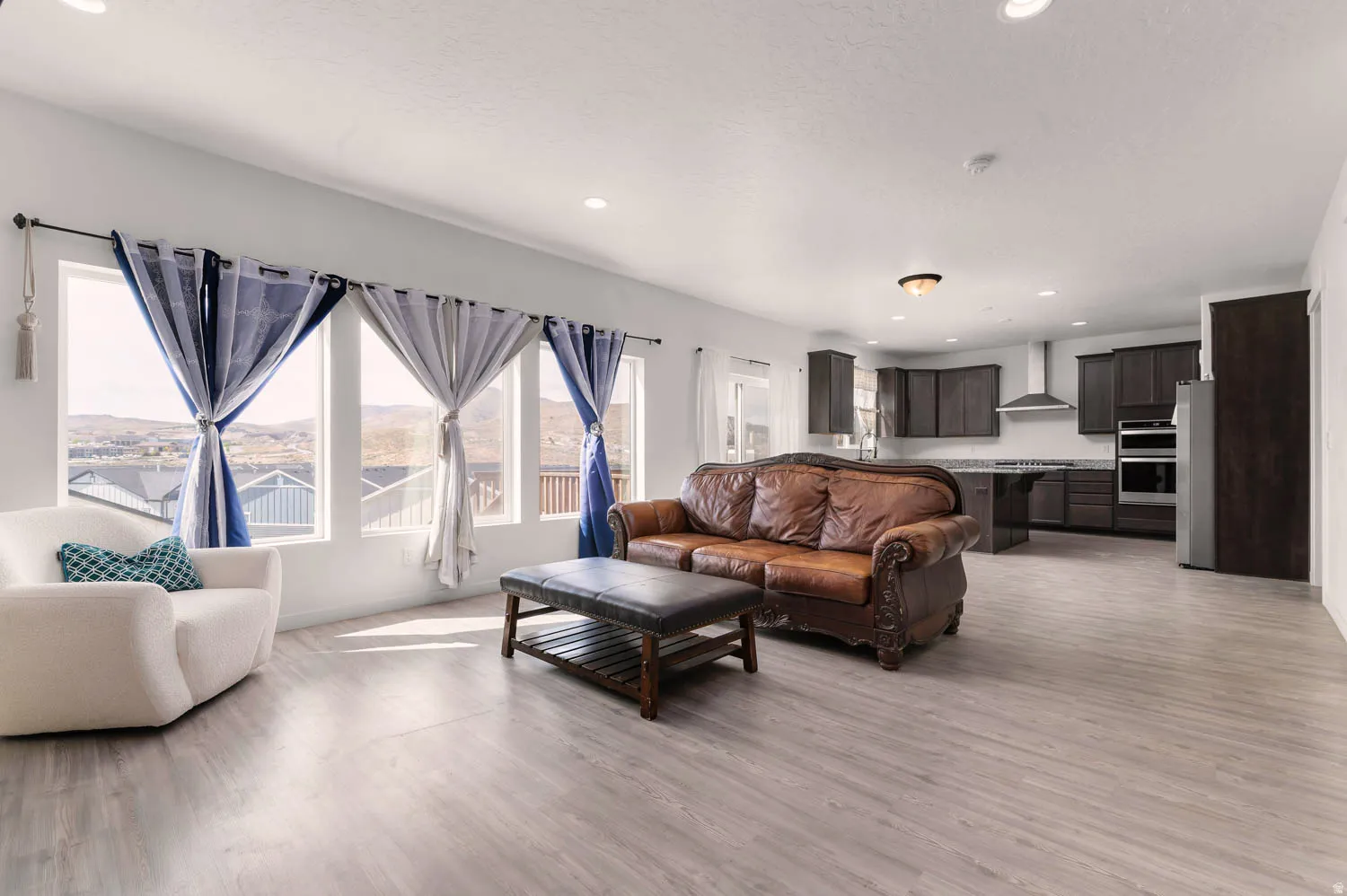 Open-concept living area featuring wood-finish flooring, recessed lighting, and a wall of windows