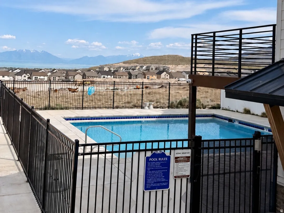 Outdoor swimming pool featuring a black metal fence, concrete decking, and steps with a handrail