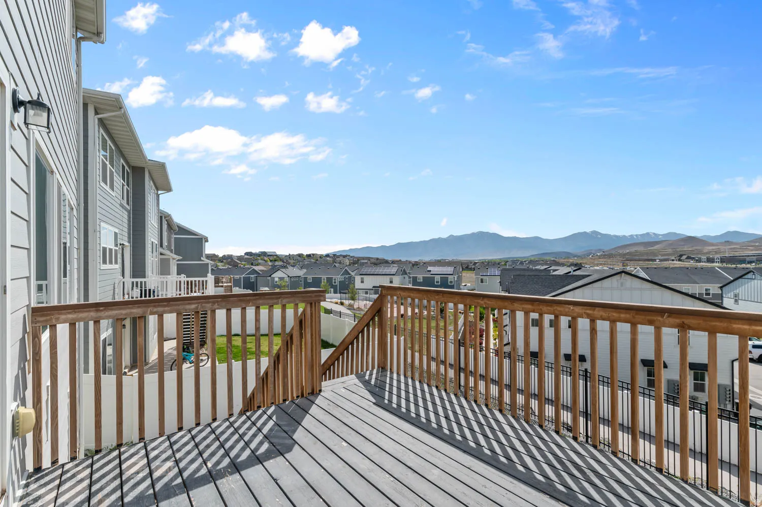 Spacious outdoor deck with wood railings, composite decking, and distant mountain scenery