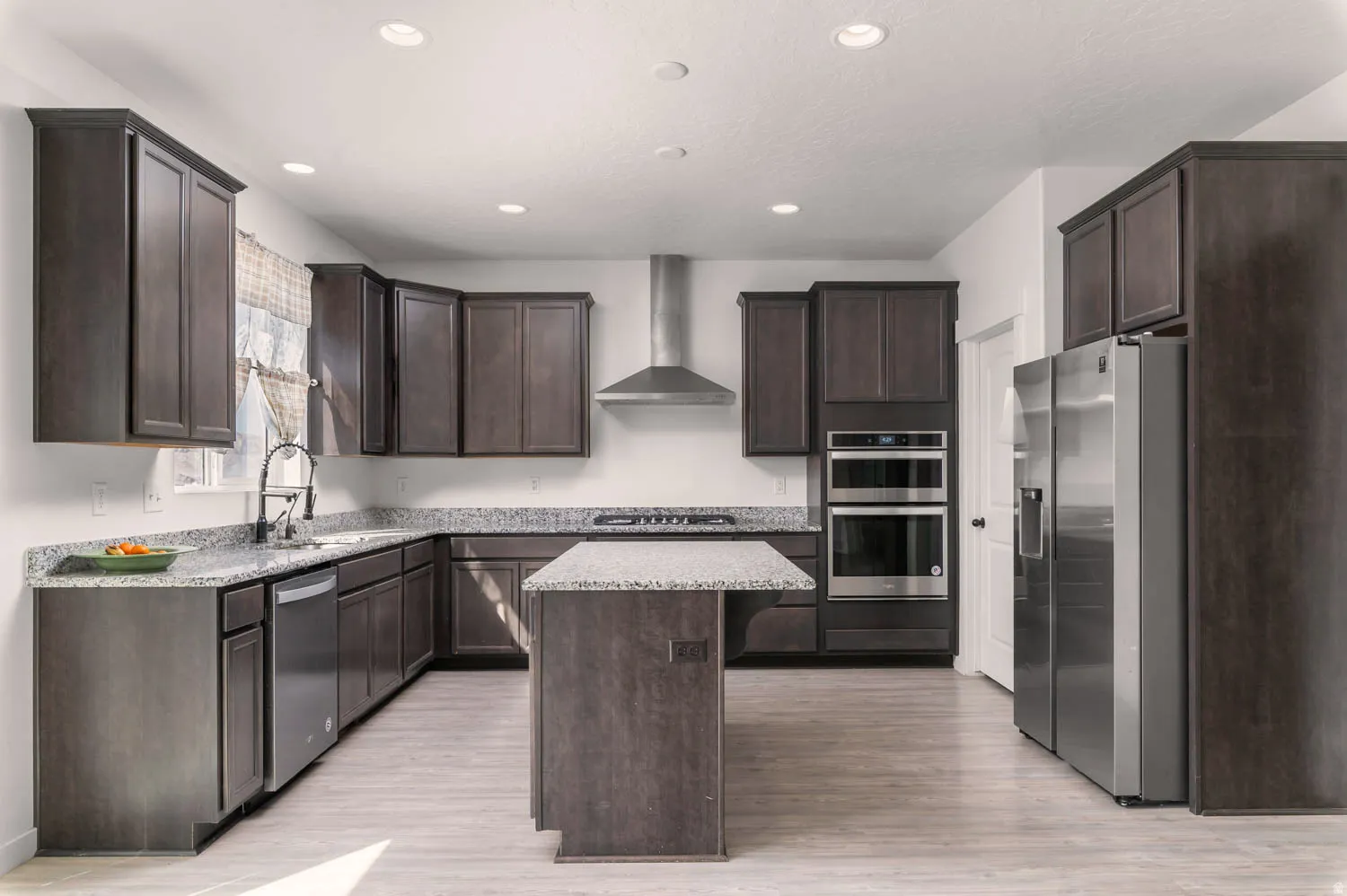 Kitchen featuring dark wood-finish cabinetry, light speckled countertops, and stainless steel appliances