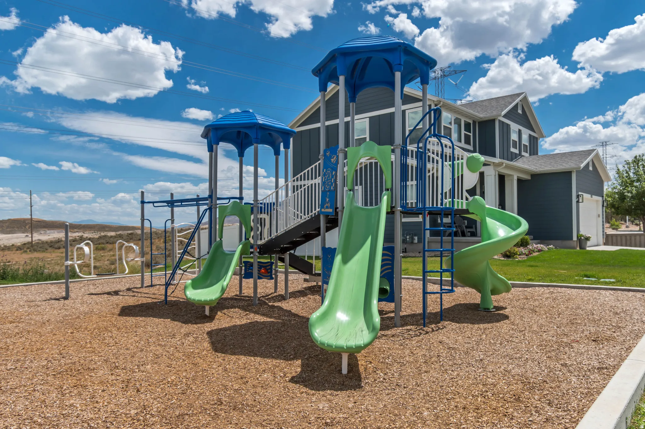 Community playground featuring multiple slides, climbing structures, and protective wood chip surfacing