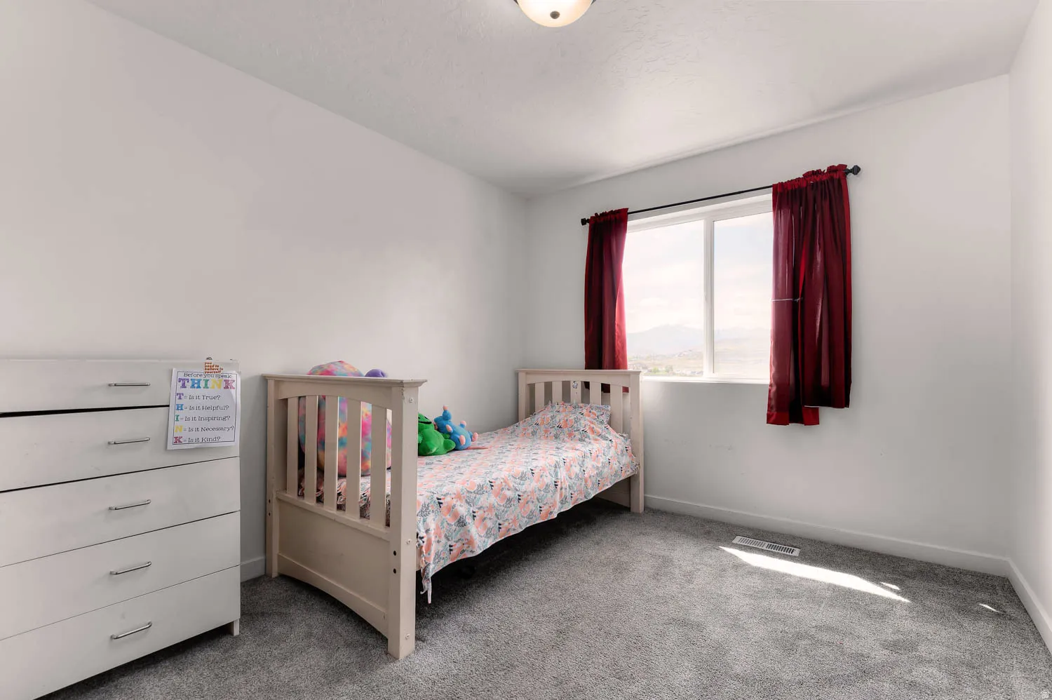 Bright room featuring a window with expansive outdoor scenery, neutral wall tones, and plush gray carpeting