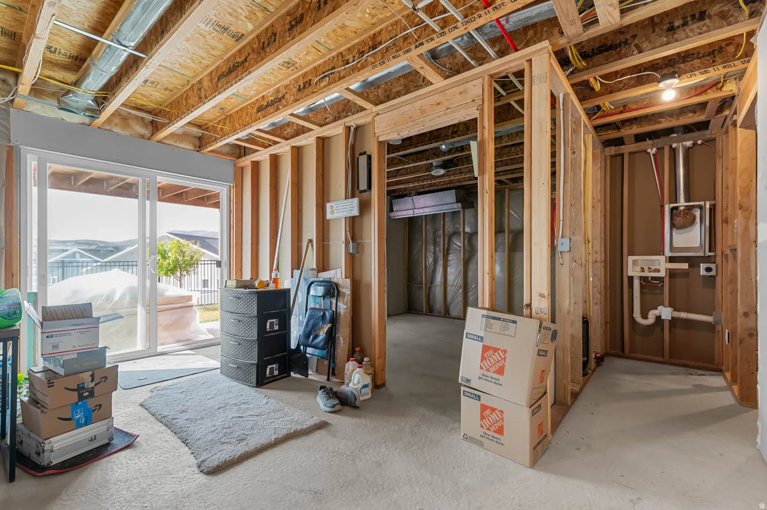 Unfinished basement featuring exposed wood framing and ceiling joists. Walkout sliding doors.
