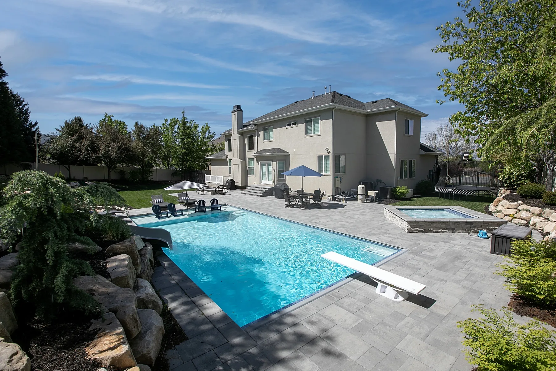 Expansive backyard featuring a rectangular swimming pool with a diving board, an integrated spa, and a built-in pool slide