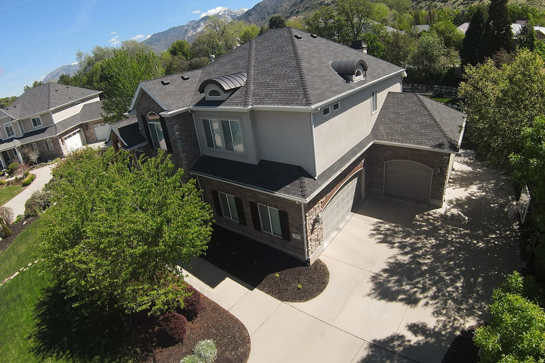 Stucco and stone exterior with architectural shingles and an arched garage door