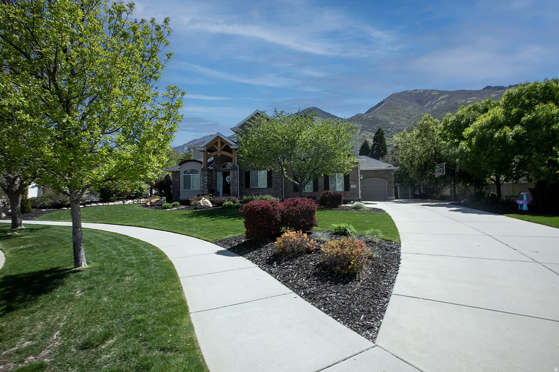 Traditional-style home featuring stone and brick façade, a gabled entry with timber accents, and a two-car garage