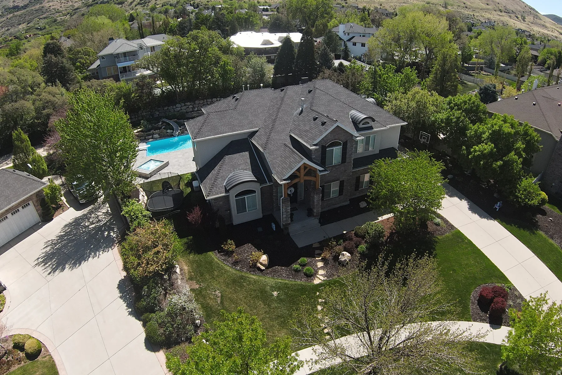 Expansive property featuring a multi-level home with a dark shingle roof, stone and siding exterior, and prominent gabled entries
