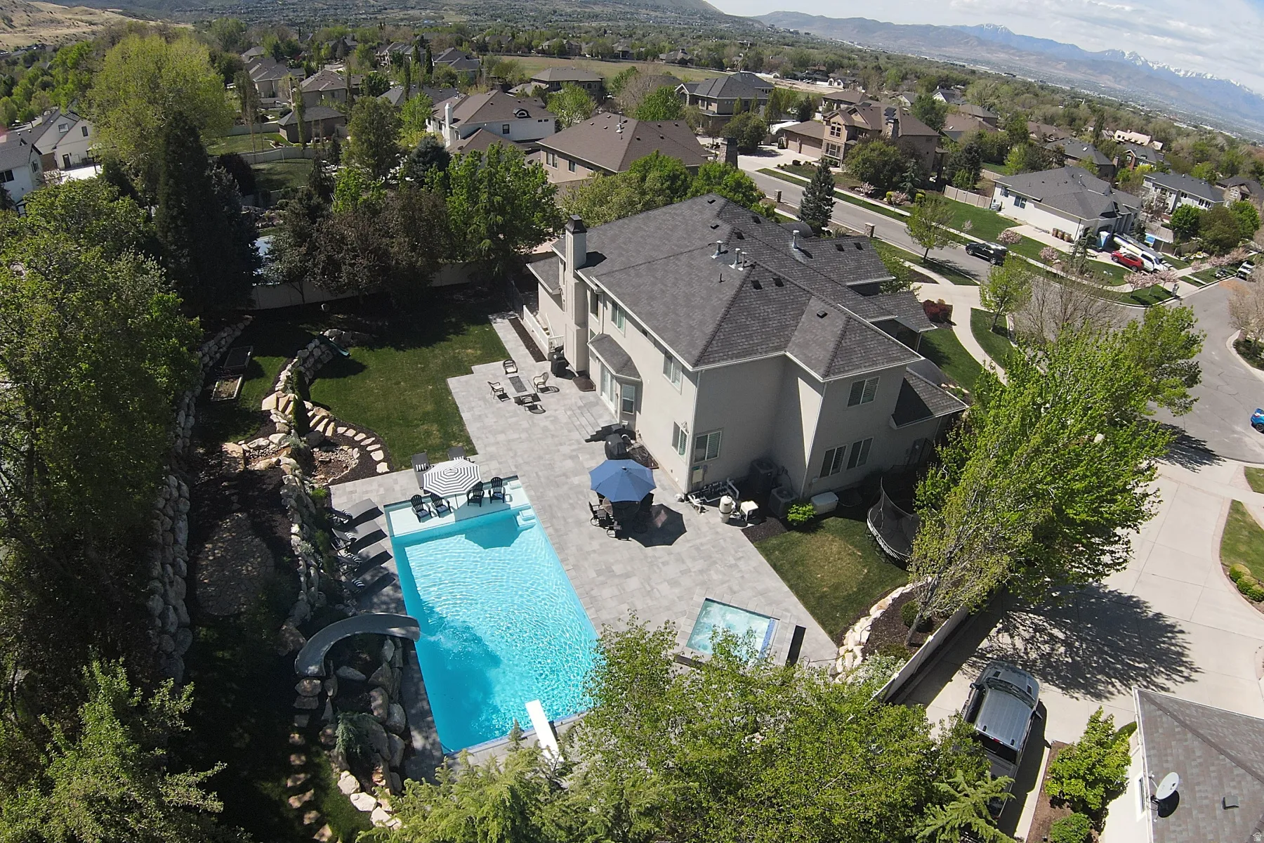 Expansive backyard featuring a large swimming pool with diving board, integrated spa, and a stone-lined water feature with slide