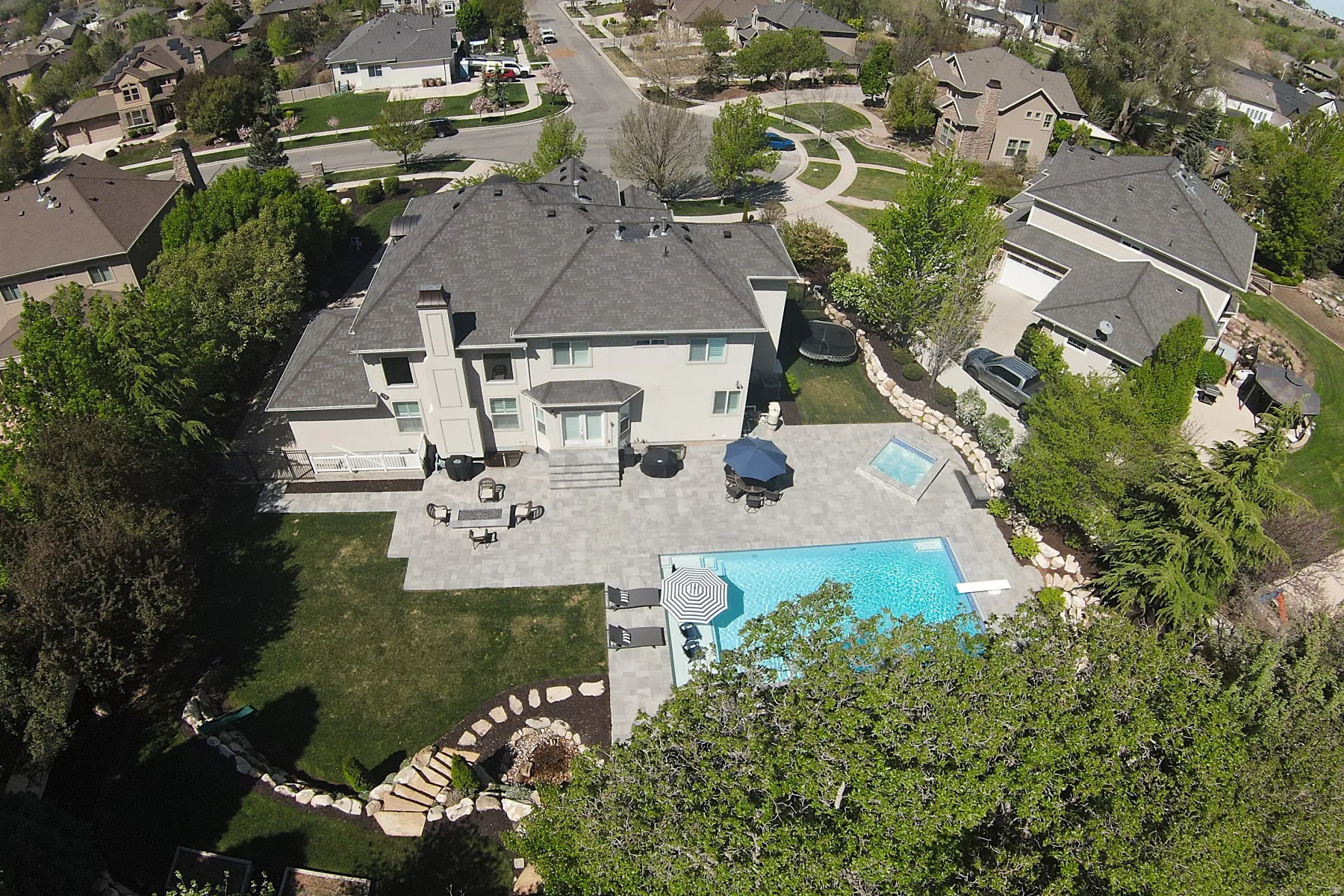 Expansive backyard featuring a large swimming pool, integrated spa, and extensive paver patio