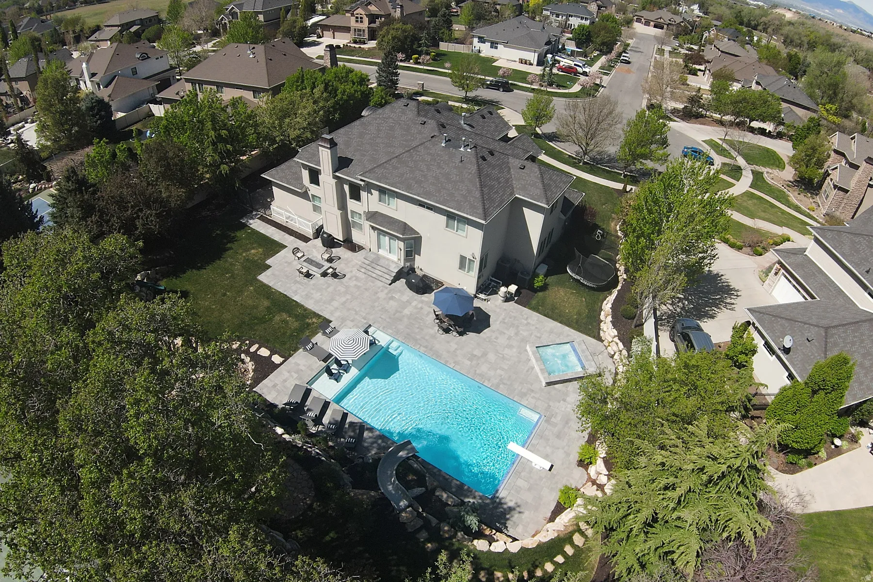 Rectangular swimming pool with integrated spa and diving board, surrounded by extensive paver patio