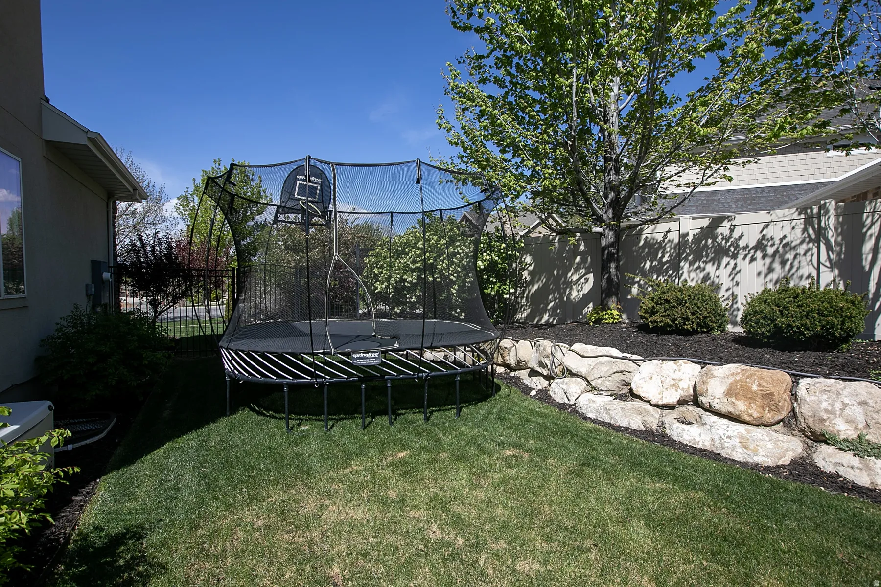 Lush green lawn with a rock retaining wall and mature trees