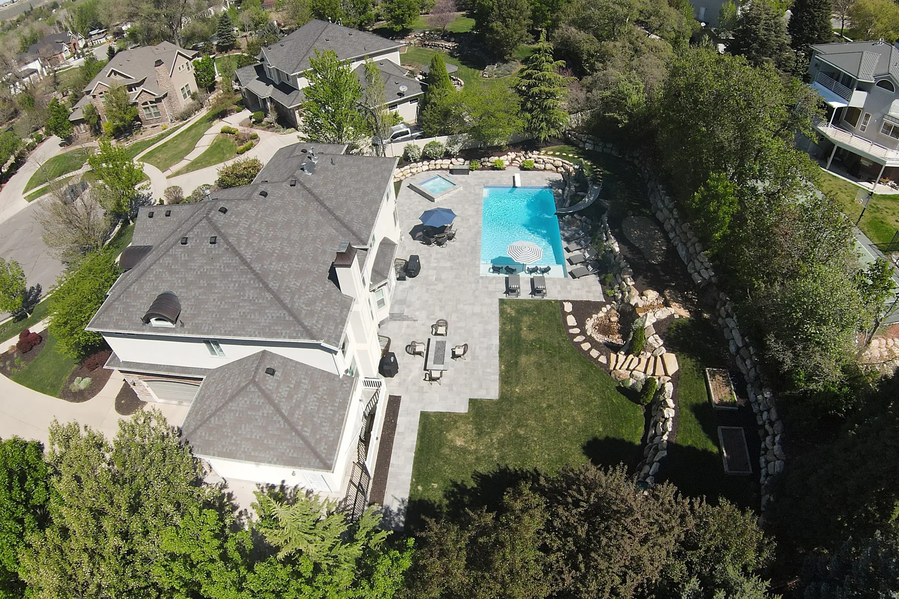 Expansive outdoor living area featuring a swimming pool, integrated spa, and spacious paver patio