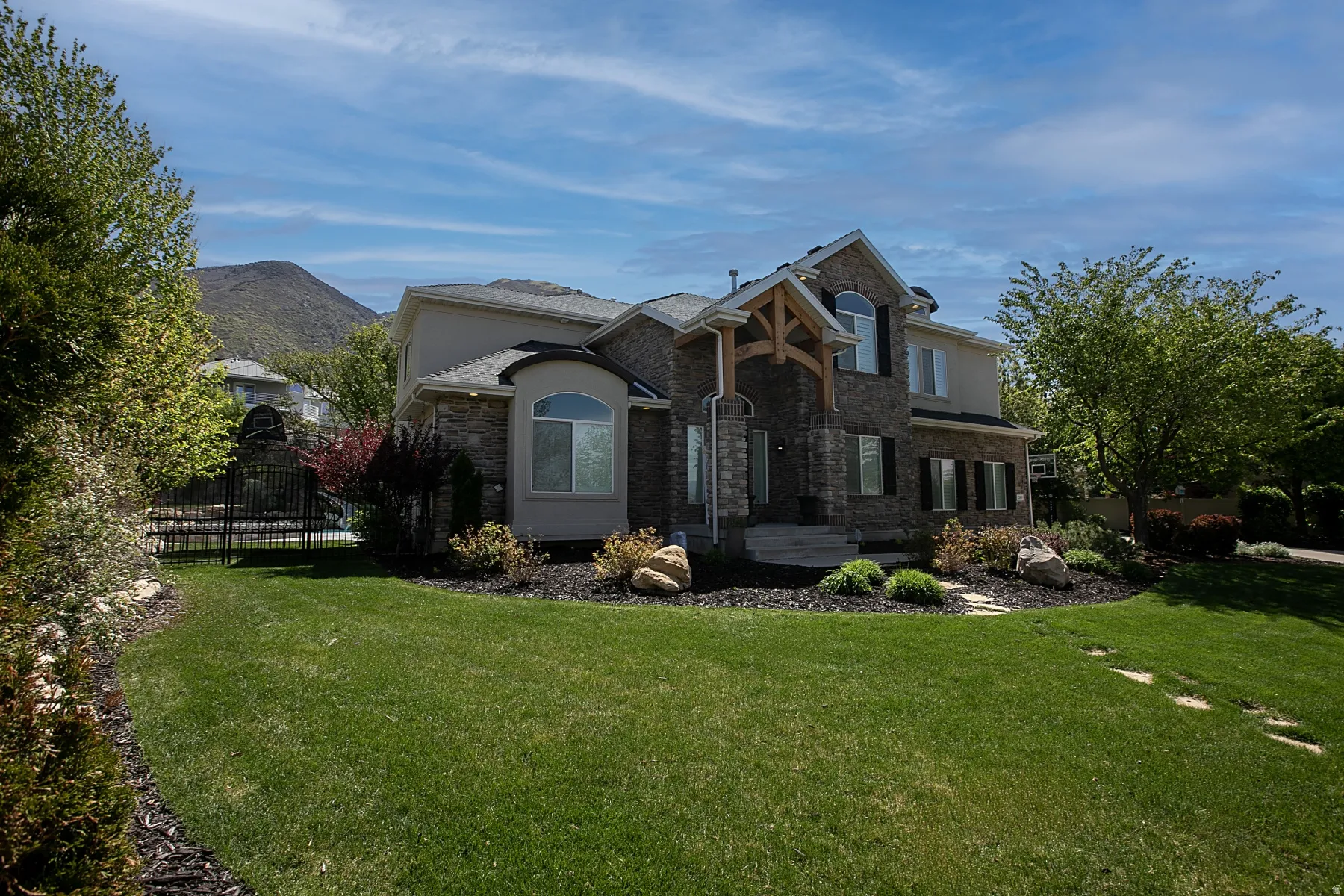 Stone and stucco exterior with dark shutters, featuring a prominent front entrance with exposed wood beams