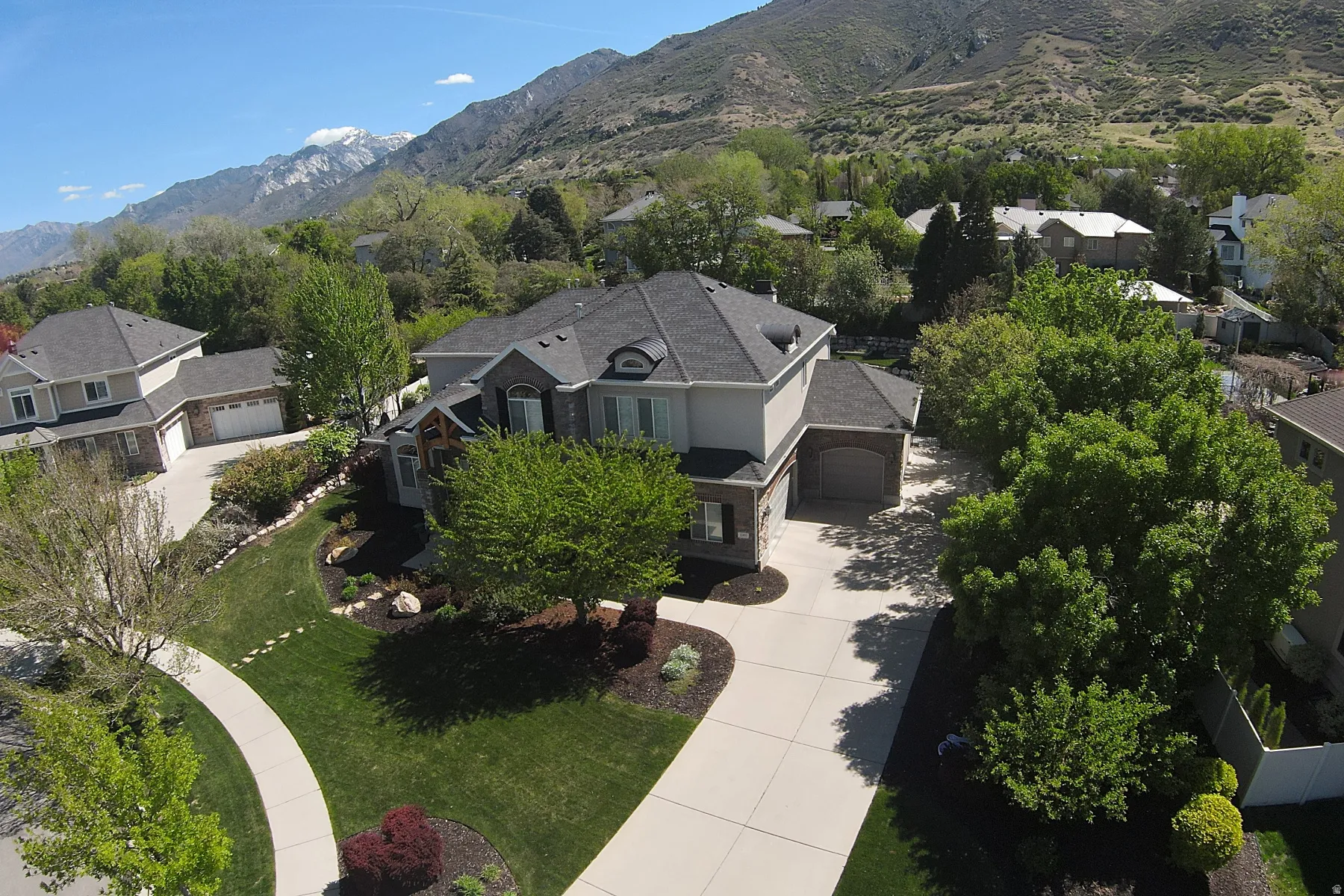 Expansive property featuring a multi-level home with a dark shingled roof, light-colored siding, and stone accents