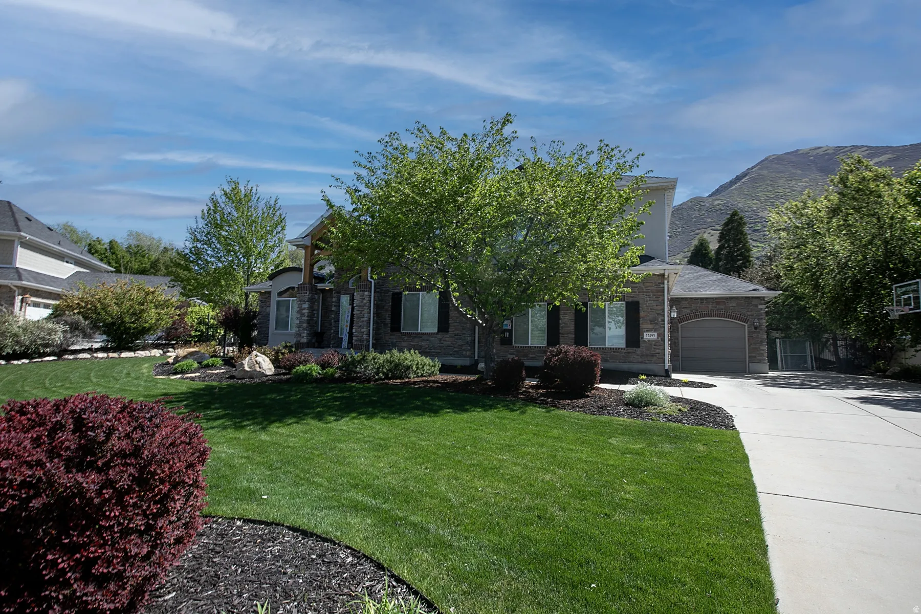 Two-story residence featuring a stone and brick exterior, a two-car garage, and a concrete driveway