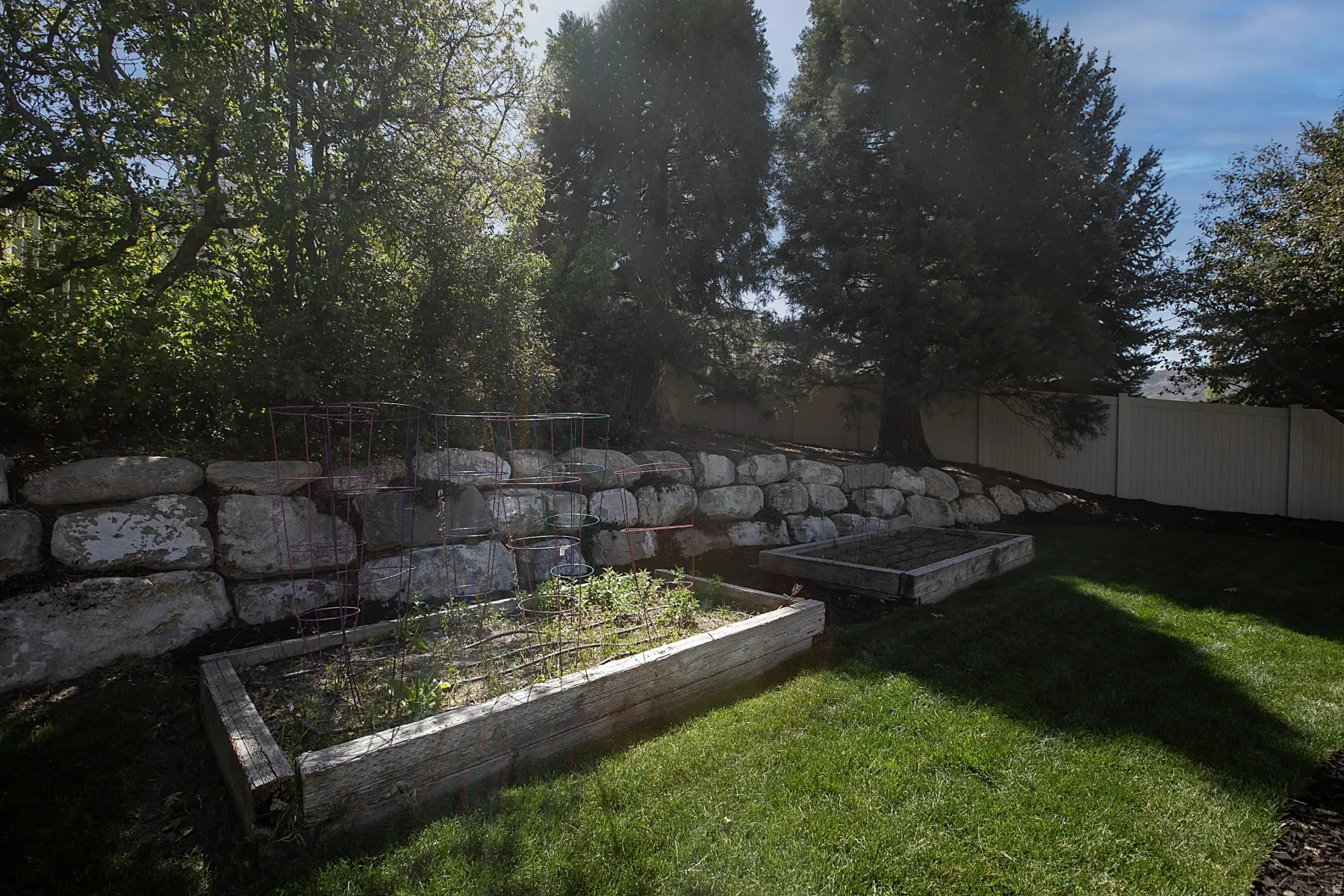 Terraced landscaping featuring a stone retaining wall, two raised garden beds, and mature trees