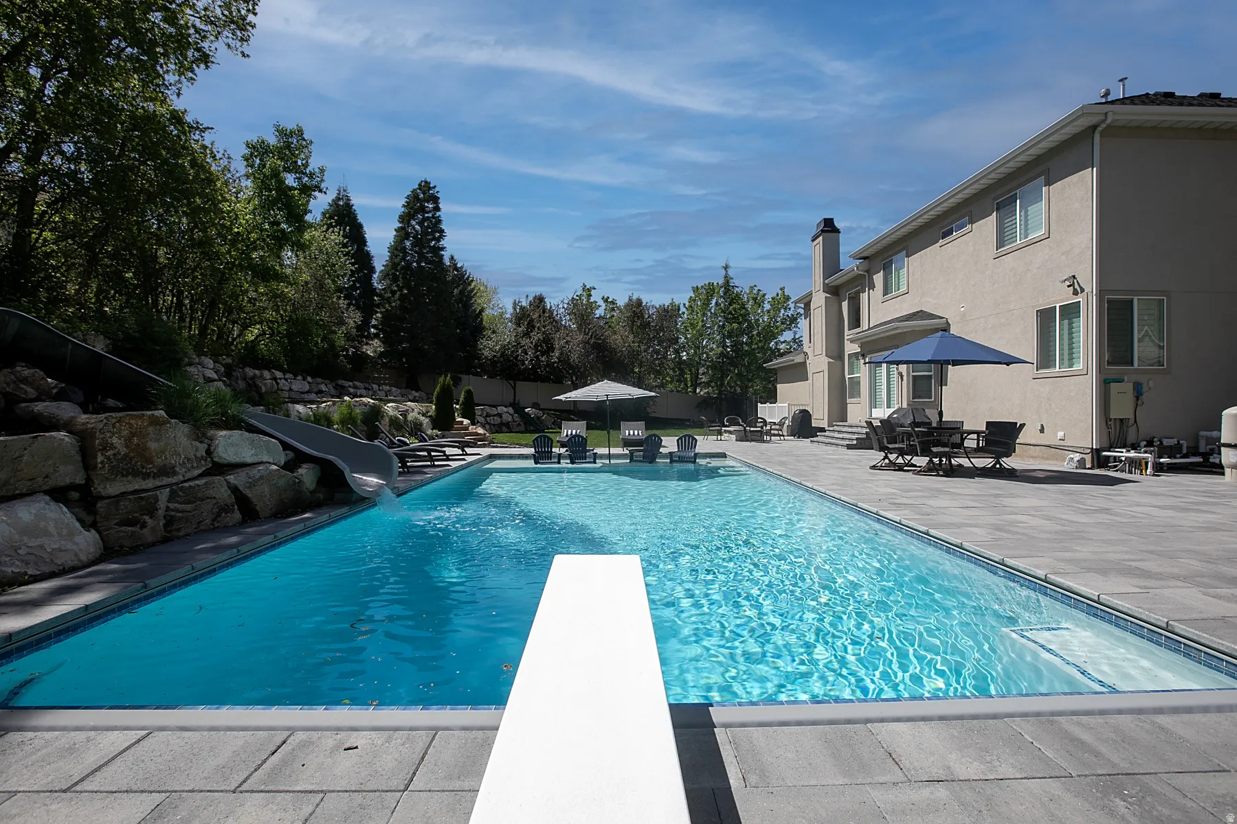Expansive outdoor area featuring a swimming pool with diving board and integrated slide
