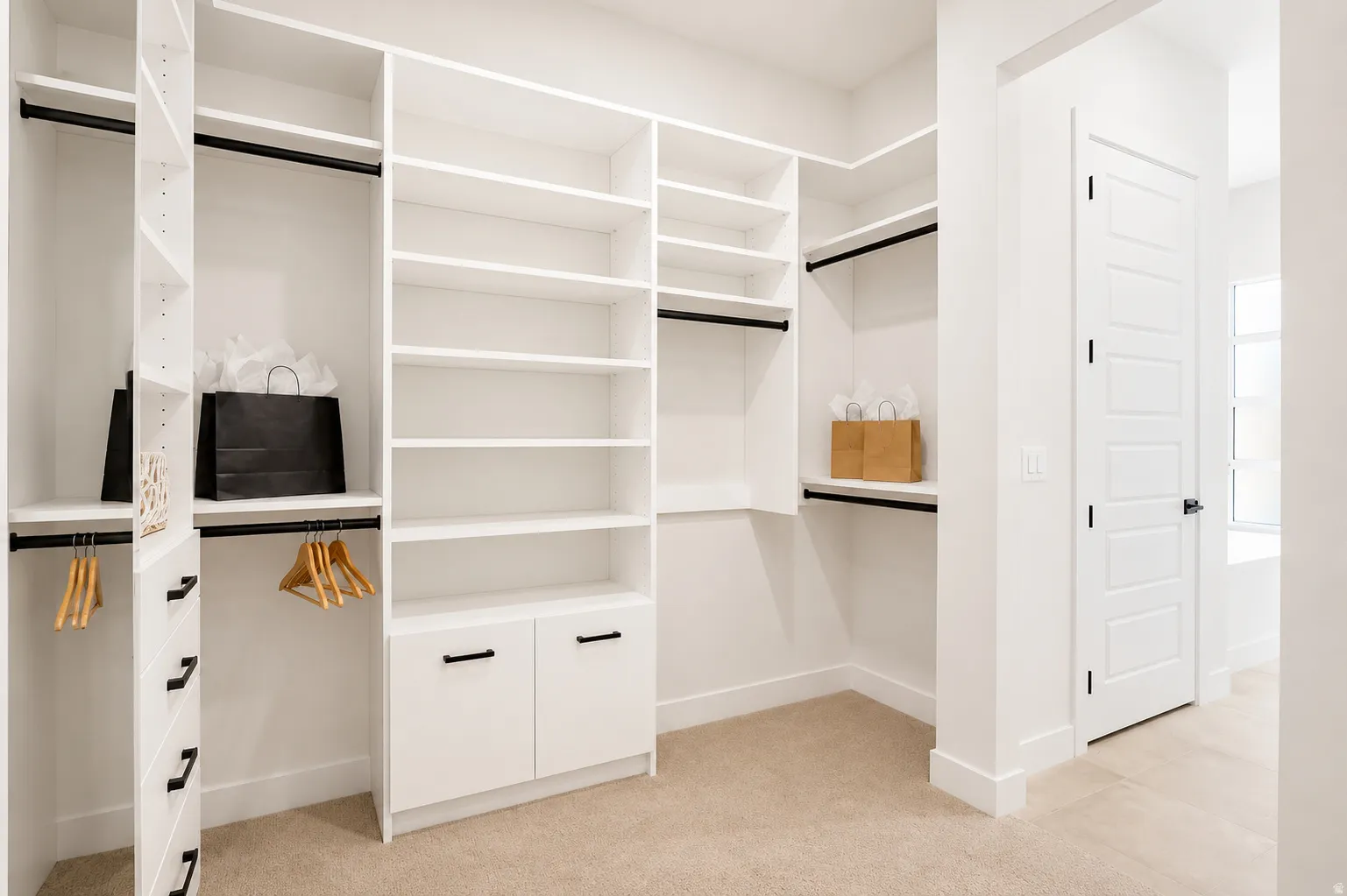 Custom closet system featuring white built-in shelving, multiple hanging rods, and integrated drawers