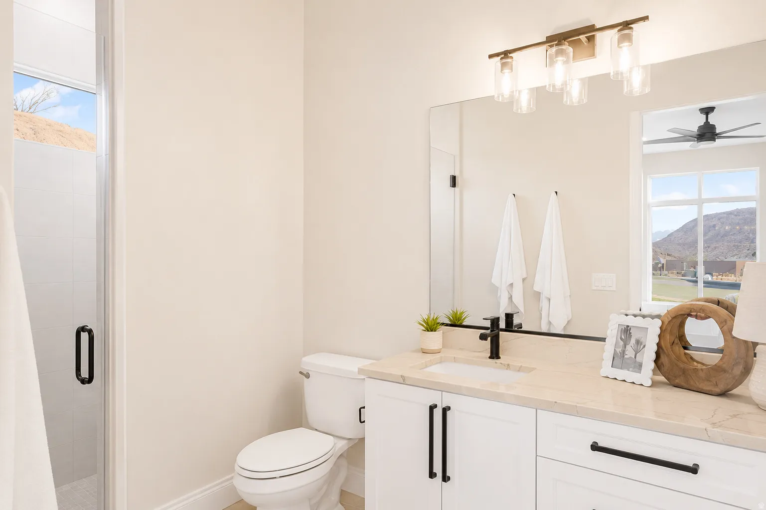 Bathroom featuring a single vanity with a light-toned countertop, white cabinetry with matte black hardware, and a large mirror