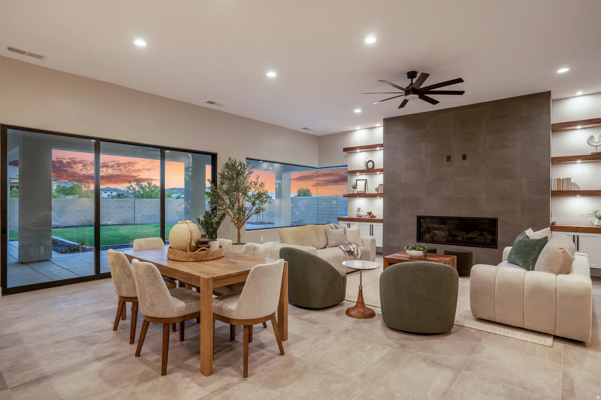 Spacious open-concept living area featuring large format tile flooring, a linear fireplace with a floor-to-ceiling tile surround, recessed lighting, and a modern ceiling fan