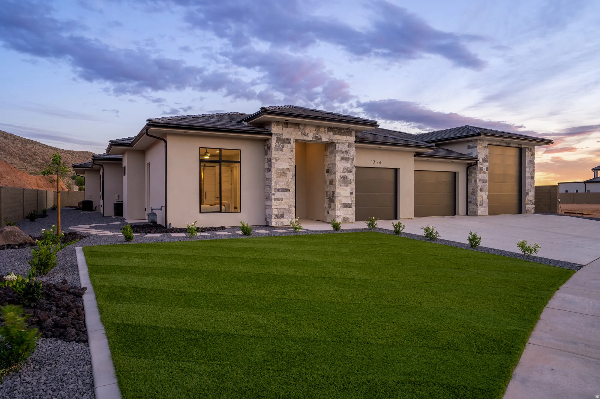 Contemporary stucco exterior with stone accents and a multi-car garage