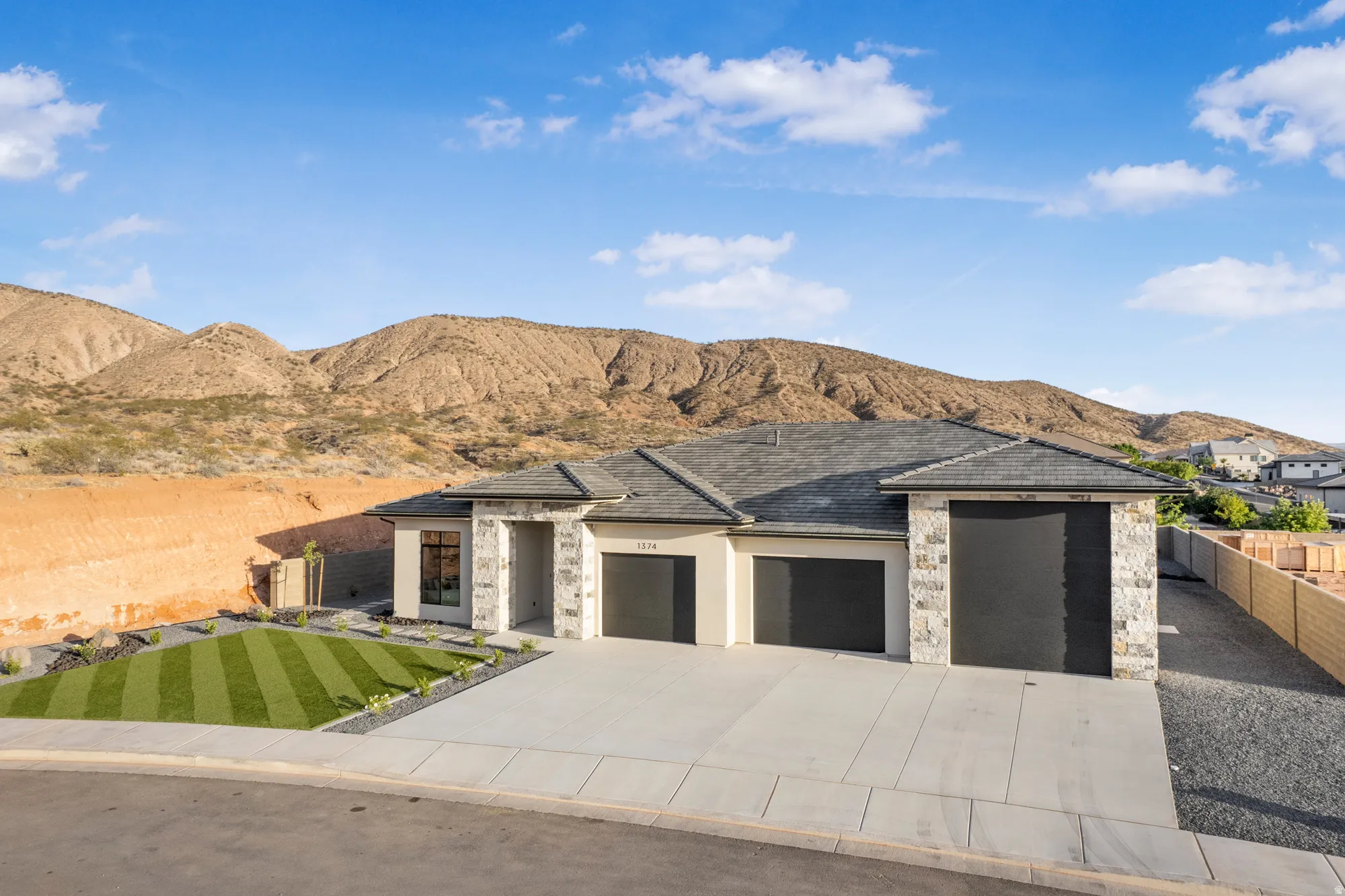 Contemporary exterior with light stucco, stone accents, and a dark shingle roof