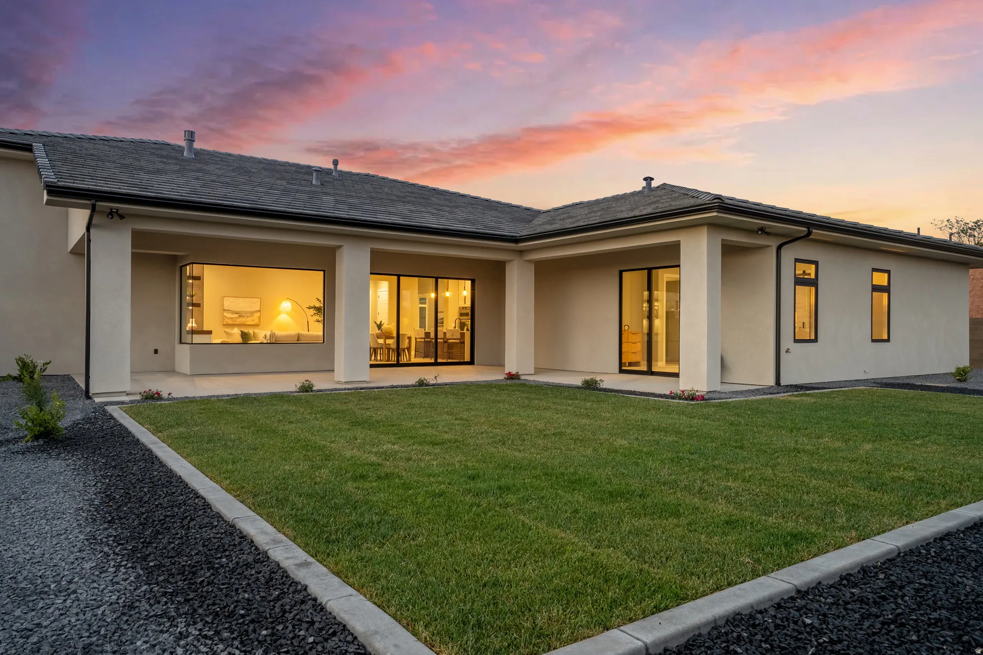 Expansive rear elevation featuring a covered patio, multiple large windows, and a generous lawn area