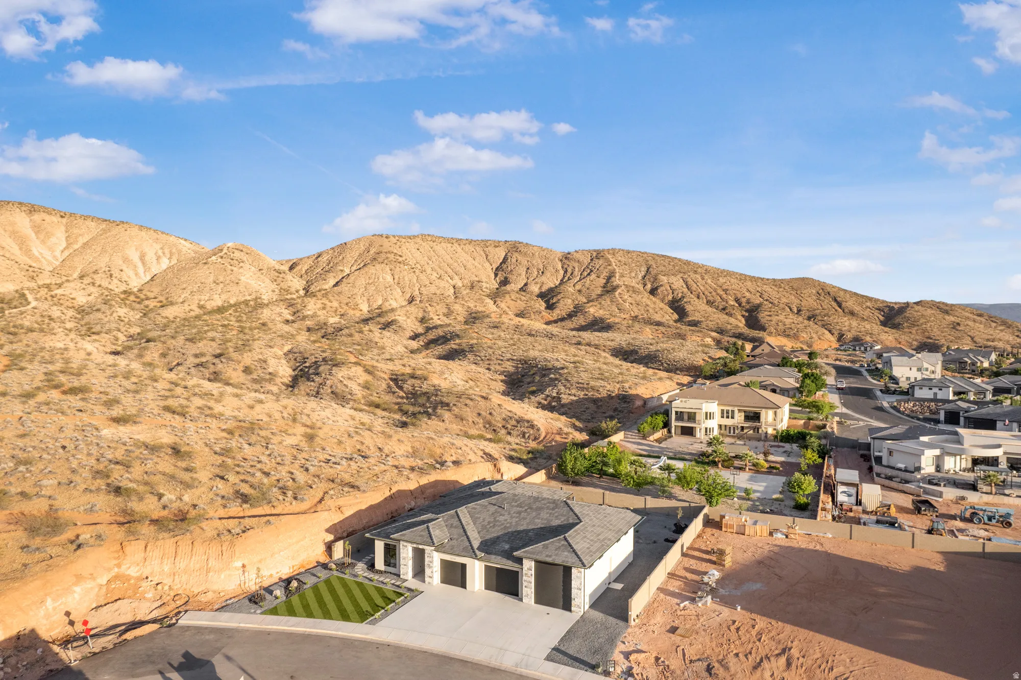 Contemporary desert-style home with a three-car garage, manicured artificial turf lawn, and a paved driveway