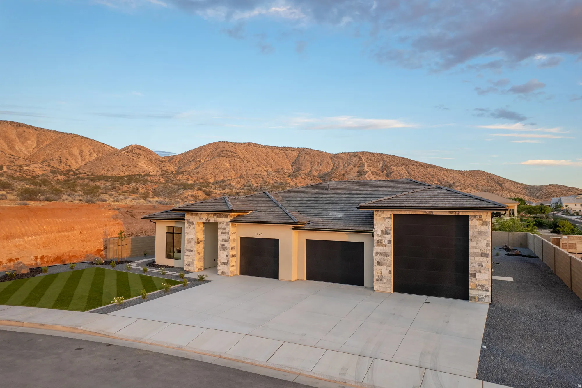 Contemporary single-story residence with a multi-car garage, stone and stucco exterior, and a manicured front lawn