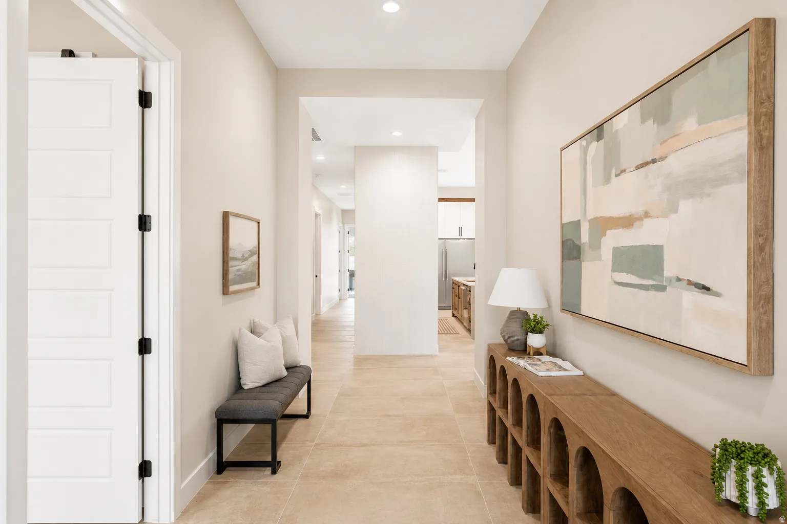 Spacious interior hallway featuring light-toned walls, recessed lighting, and large format tile flooring