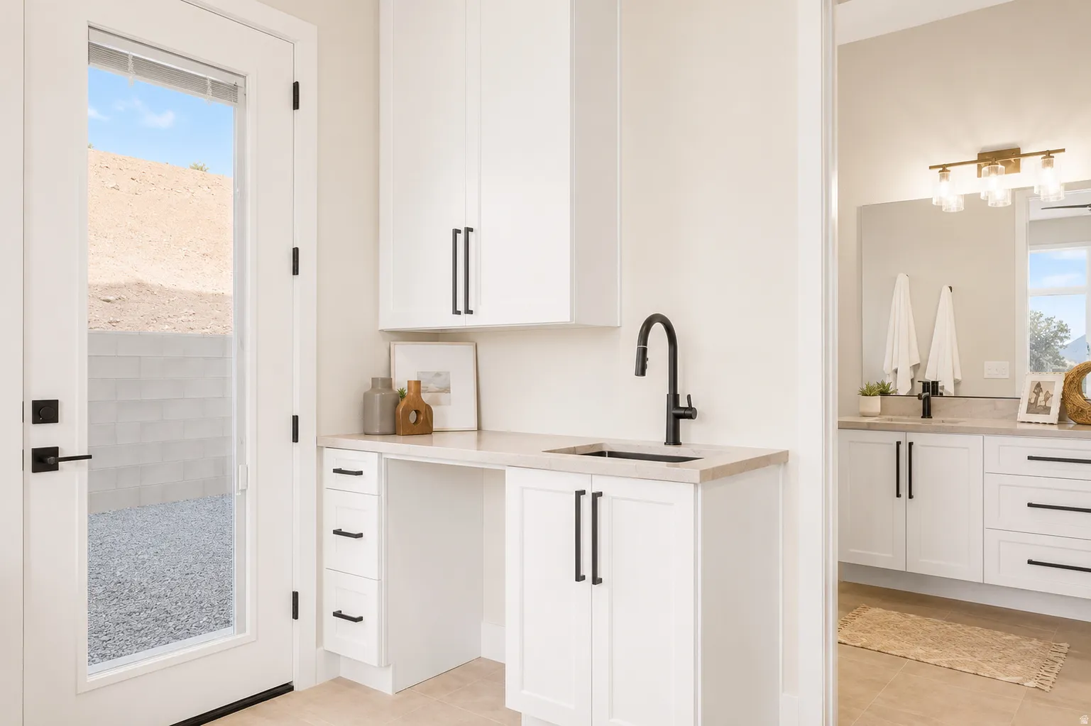 Modern utility space featuring white cabinetry with matte black hardware, a light-toned countertop, and a built-in sink with a matte black faucet