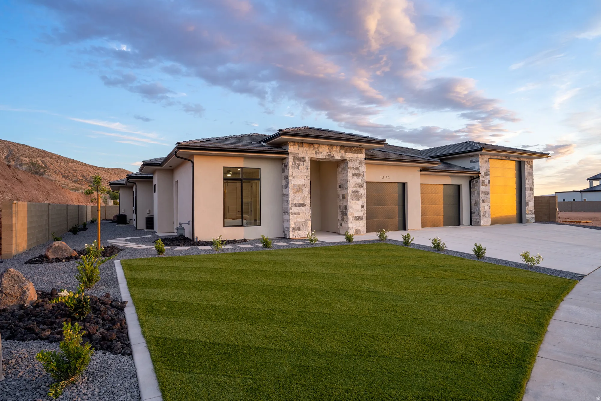 Contemporary stucco exterior with stone accents, featuring a multi-car garage