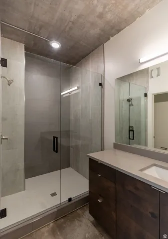 Full glass-enclosed shower with gray tiled walls and white mosaic floor