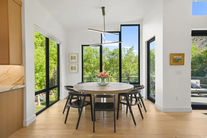 Dining area featuring abundant natural light, light wood-finish flooring, and a modern linear chandelier