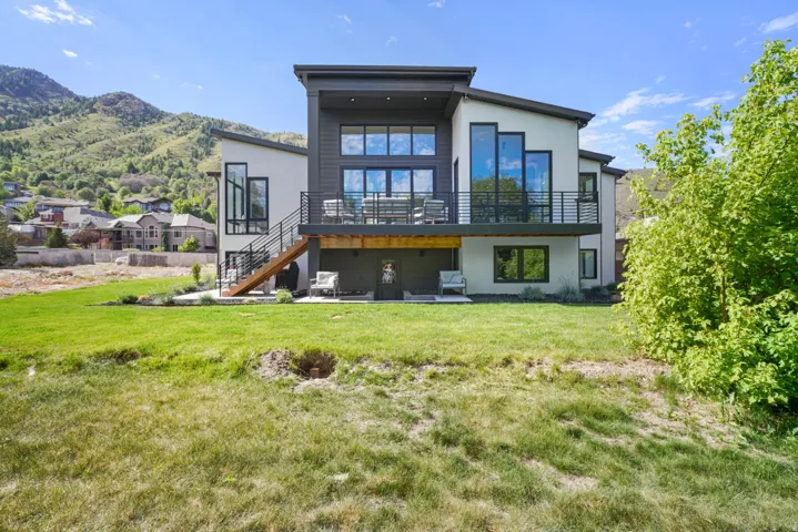 Contemporary architecture featuring a multi-level design with a large upper balcony and ground-level patio