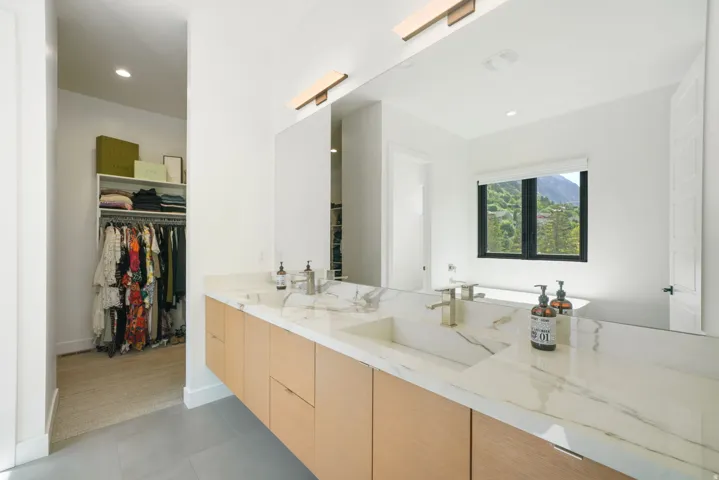 Floating dual vanity with integrated sinks, light wood-finish cabinetry, and a stone-patterned countertop