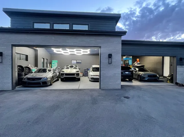 Multi-bay garage featuring modern hexagonal ceiling lighting, dark brick exterior accents, and an asphalt driveway