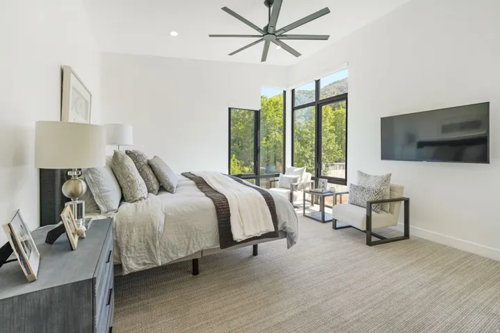 Bedroom featuring expansive windows with mountain and tree scenery, modern ceiling fan, recessed lighting, and light-toned carpeting