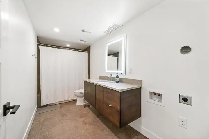 Modern bathroom featuring a floating wood-finish vanity with an integrated sink and light-framed mirror