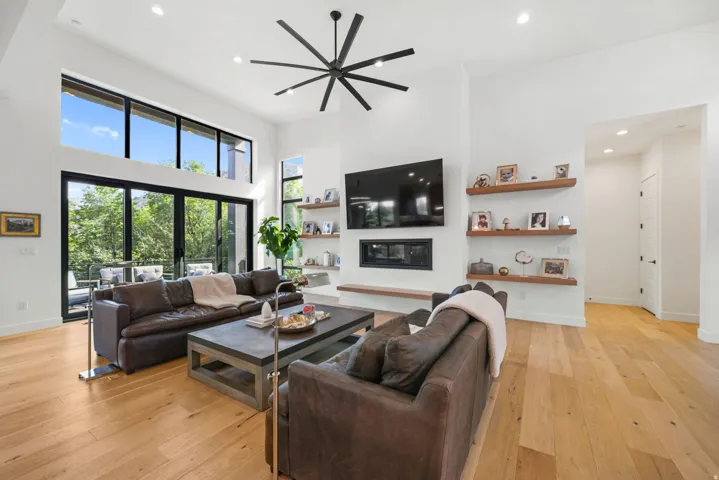 Spacious living area featuring high ceilings, wood-finish flooring, and a linear fireplace with a hearth