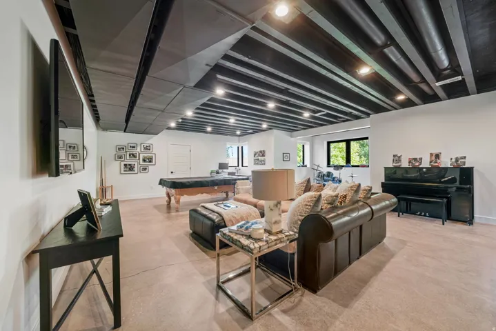 Expansive room featuring painted exposed ceiling beams, recessed lighting, and concrete flooring