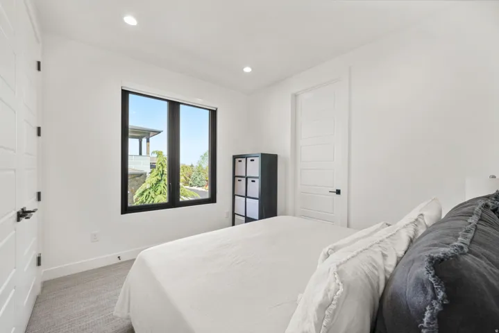 Light-filled room featuring a large black-framed window, recessed lighting, white panel doors with black hardware, and neutral-toned carpeting