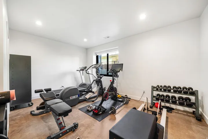Dedicated fitness room featuring recessed lighting, a compact window, and light-toned walls
