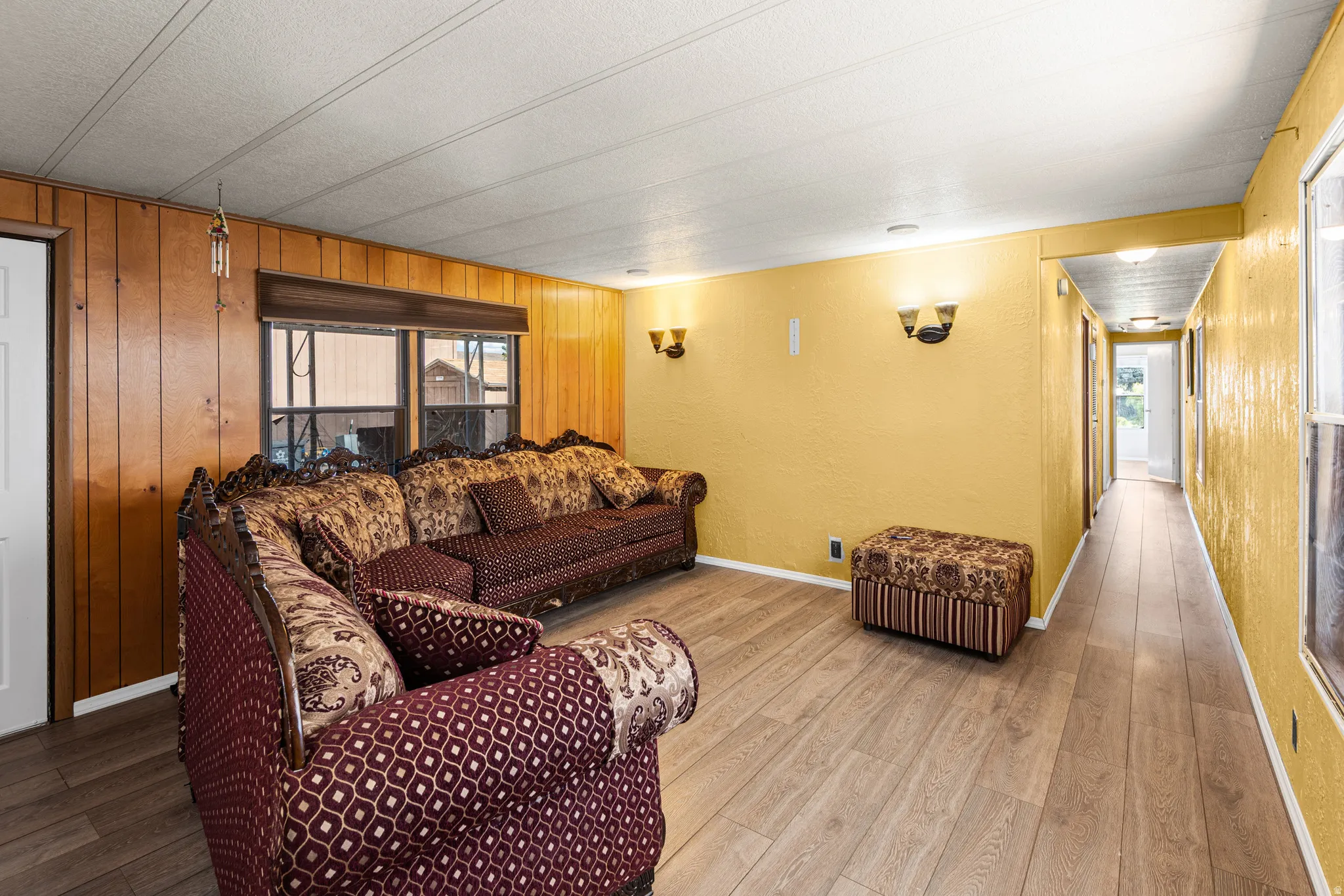 Living area featuring wood-finish flooring, a white paneled ceiling, and a prominent window with a dark frame